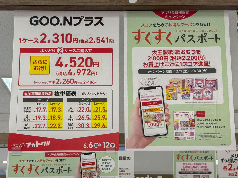 『GOO.Nプラス』のおむつ価格と、すくすくパスポートキャンペーンの案内を掲載した店頭ポスター。1ケース税込2,541円、2ケース購入で割引、1枚単価の比較表やスマホアプリによるクーポン取得情報も記載されている。